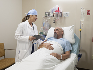 Healthcare provider talking to man in pre-op hospital room.